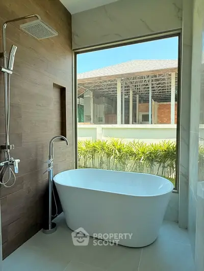 Luxurious bathroom with freestanding bathtub and large window view of construction site.