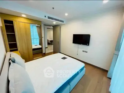 Modern bedroom with wooden flooring, wall-mounted TV, and mirrored wardrobe in a stylish apartment.