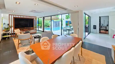 Luxurious open-plan living room with pool view, modern furniture, and elegant dining area.