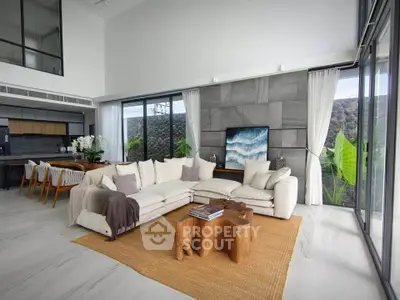 Luxurious open-plan living room with modern decor and natural light, featuring a cozy sectional sofa and stylish wooden table.