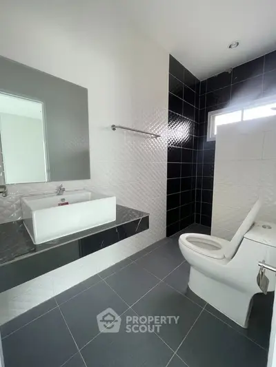 Modern bathroom with sleek black and white tiles and contemporary fixtures.