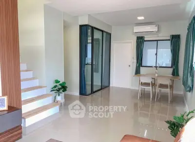Modern living room with dining area and staircase, featuring sleek design and natural light.