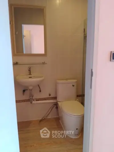 Compact bathroom with modern fixtures and neutral tiles, featuring a wall-mounted sink and toilet.