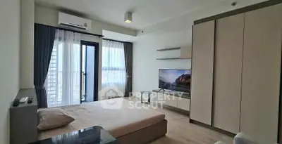 Modern bedroom with large window and city view, featuring sleek furniture and neutral tones.
