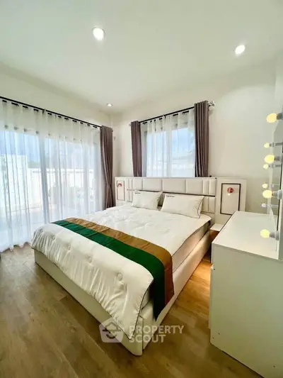 Spacious and bright bedroom with modern decor and large windows.
