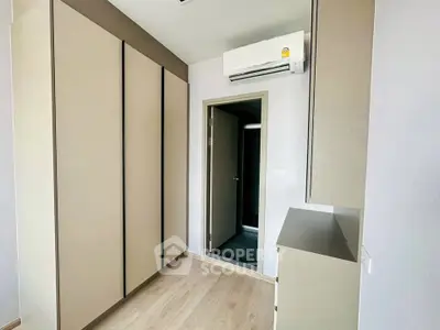 Modern bedroom with built-in wardrobe and air conditioning unit, featuring sleek design and neutral tones.