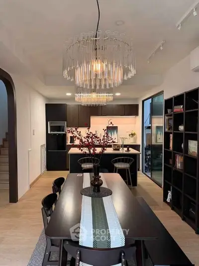 Elegant dining area with modern chandelier and open kitchen layout, perfect for entertaining.