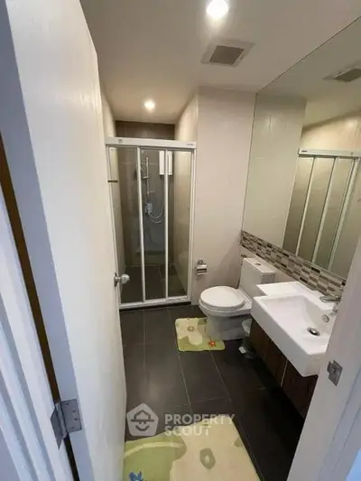 Modern bathroom with glass shower, sleek sink, and stylish tiles.