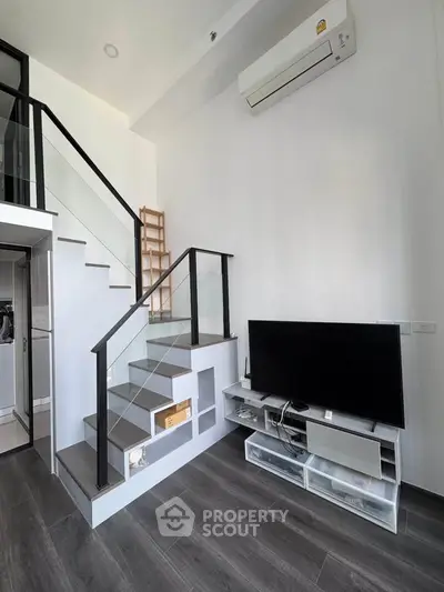 Modern loft-style living room with sleek staircase and wall-mounted TV