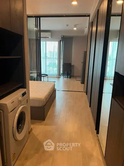 Modern apartment interior with bedroom and washing machine, featuring sleek design and ample natural light.