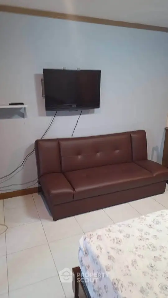 Cozy living room with wall-mounted TV and brown leather sofa
