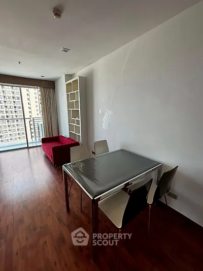 Modern living room with wooden flooring and balcony view in urban apartment.