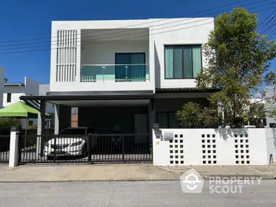 Modern two-story house with carport and balcony in a suburban neighborhood.