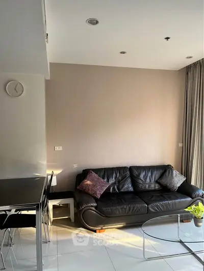 Modern living room with black leather sofa and glass coffee table