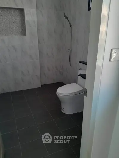 Modern bathroom with sleek design and tiled walls, featuring a shower and toilet.