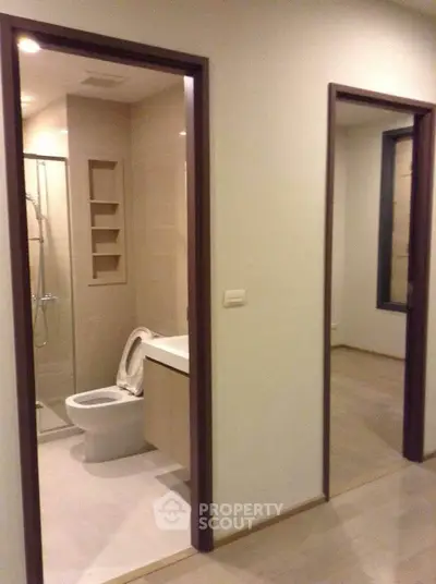 Modern apartment interior with bathroom and hallway view, showcasing sleek design and neutral tones.