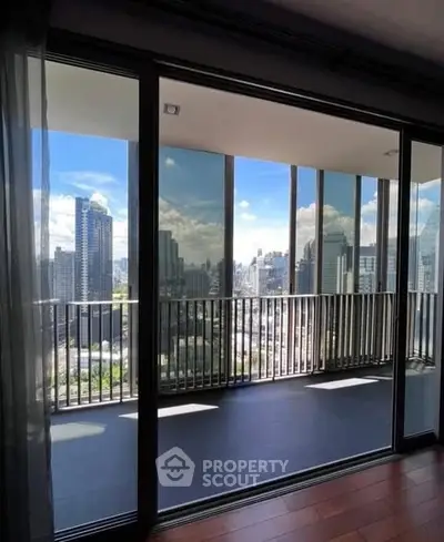 Stunning cityscape view from a modern high-rise balcony with floor-to-ceiling glass doors.