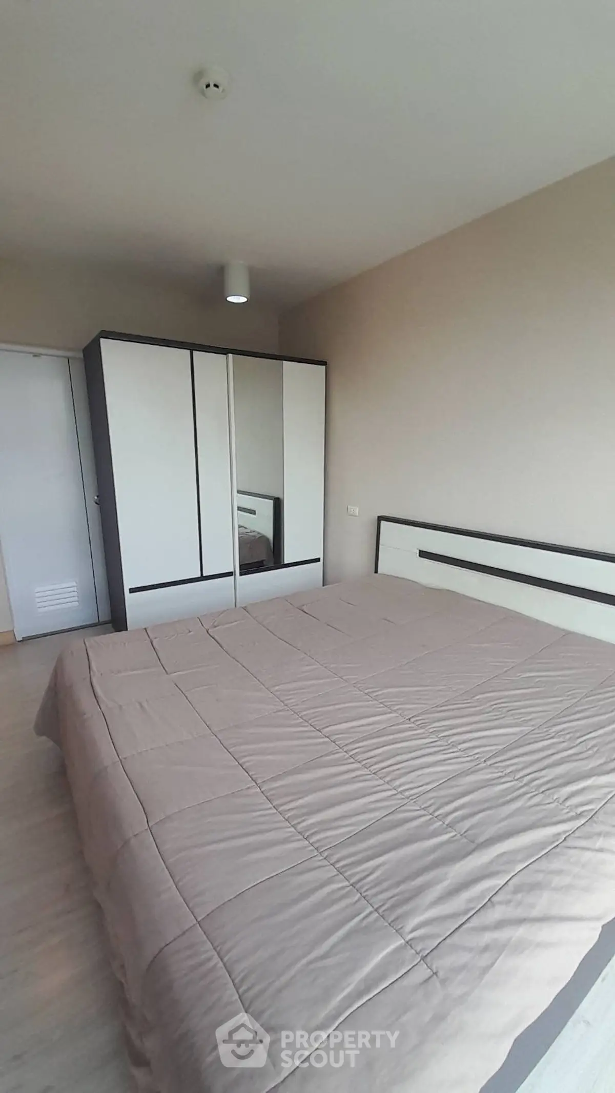 Spacious bedroom with modern wardrobe and cozy bedding in a stylish apartment.