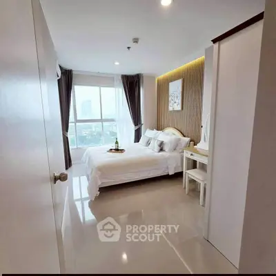 Modern bedroom with city view, elegant decor, and natural light in a high-rise apartment.