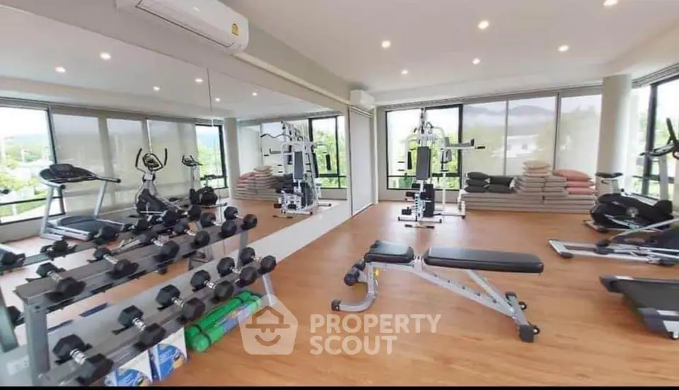 Modern gym with panoramic windows and fitness equipment in luxury apartment complex