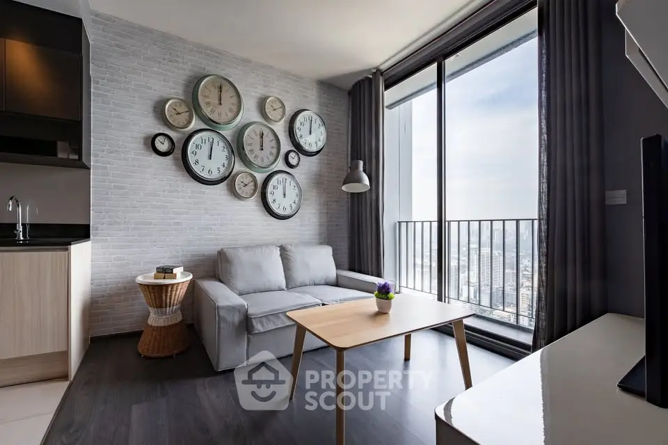 Modern living room with large windows and city view, featuring stylish clock wall decor and cozy seating area.