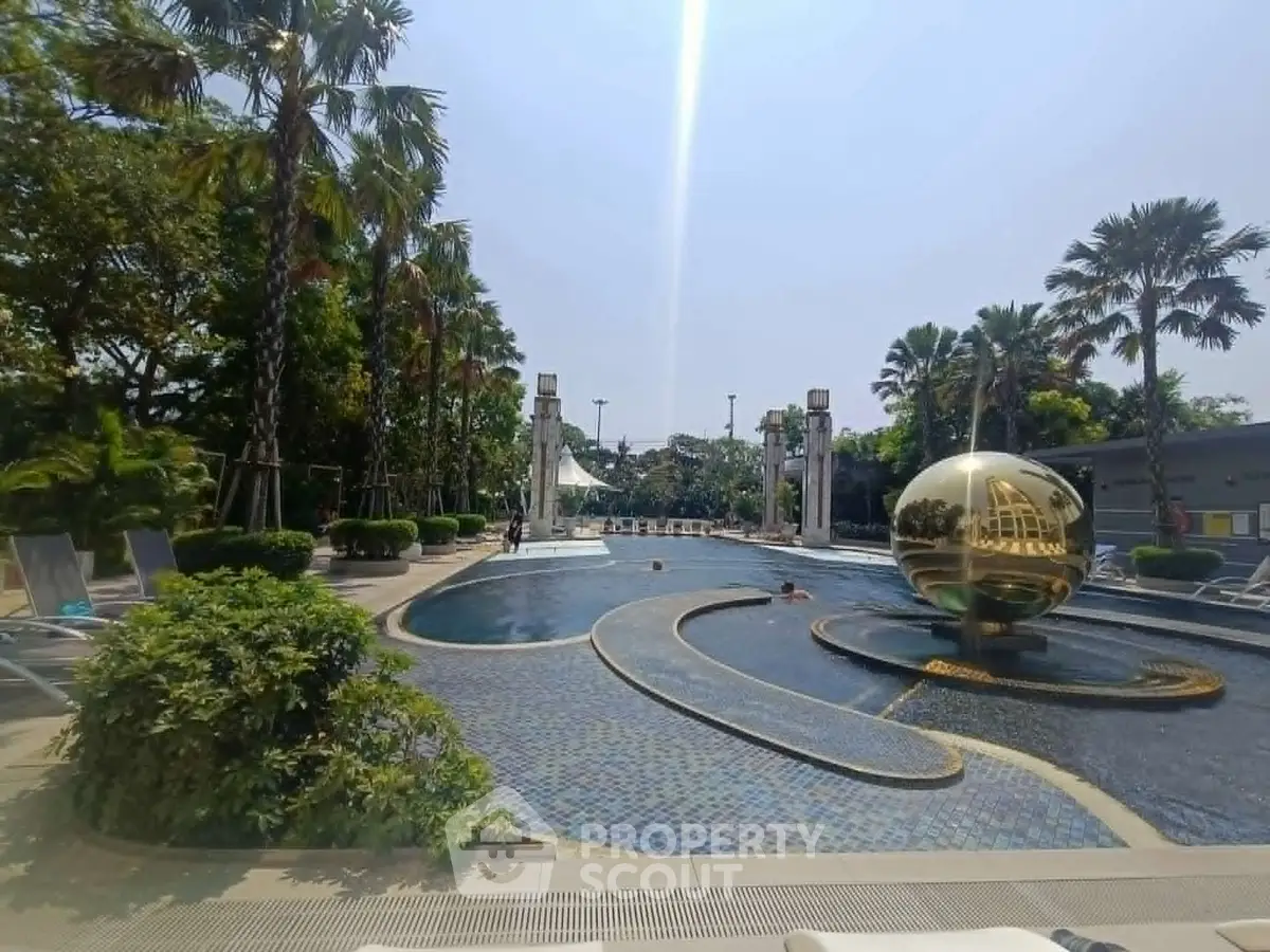 Luxurious outdoor pool area with palm trees and unique golden globe sculpture, perfect for relaxation.