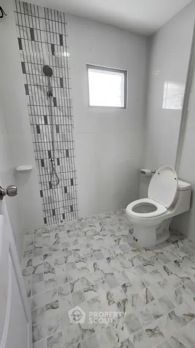 Modern bathroom with tiled shower and window, featuring a sleek design and neutral tones.