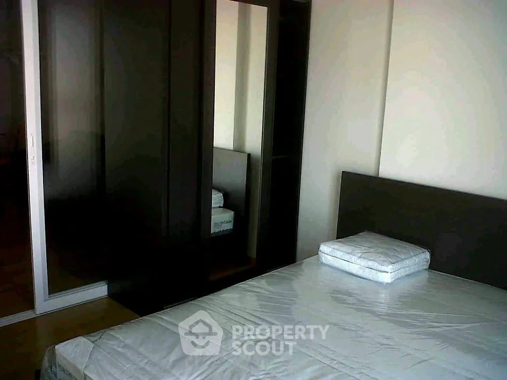 Modern bedroom with sleek dark wardrobe and minimalist bed setup.