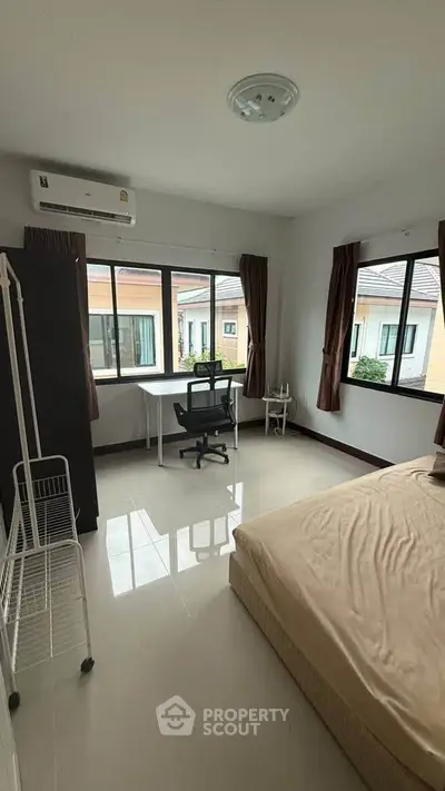 Spacious bedroom with large windows and modern furnishings for a comfortable living experience.