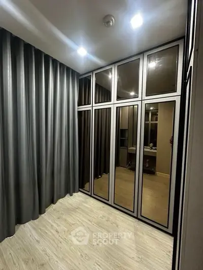 Modern walk-in closet with mirrored doors and elegant lighting