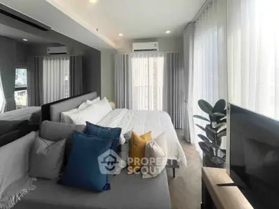 Modern bedroom with large windows, stylish decor, and natural light in a high-rise apartment.