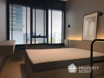 Modern bedroom with ample natural light, sleek furniture, and a serene city view through large windows with stylish blinds.