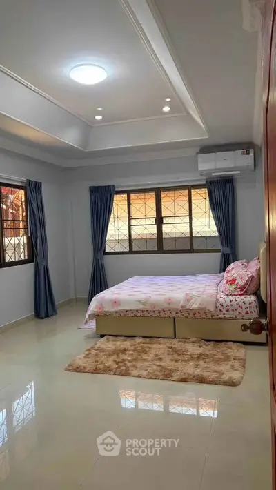 Spacious bedroom with large windows and elegant decor in modern home.