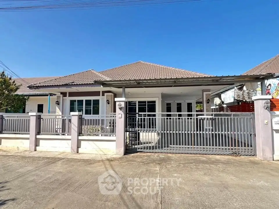 Charming single-story house with gated entrance and tiled roof under clear blue sky.