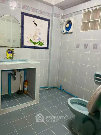 Charming bathroom with tiled walls and unique decor, featuring a sink and toilet.