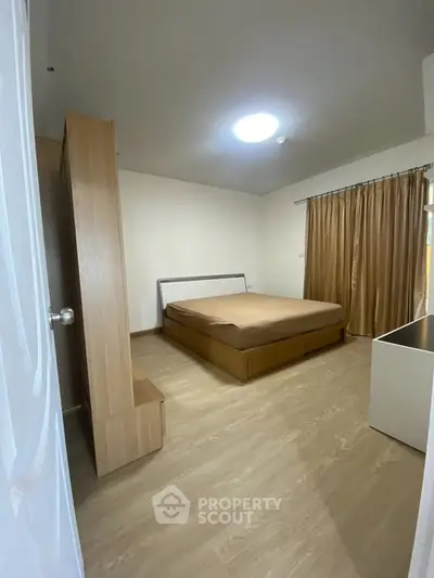 Spacious bedroom with wooden flooring and modern furnishings