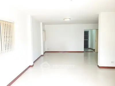 Spacious empty living room with white walls and tiled floor