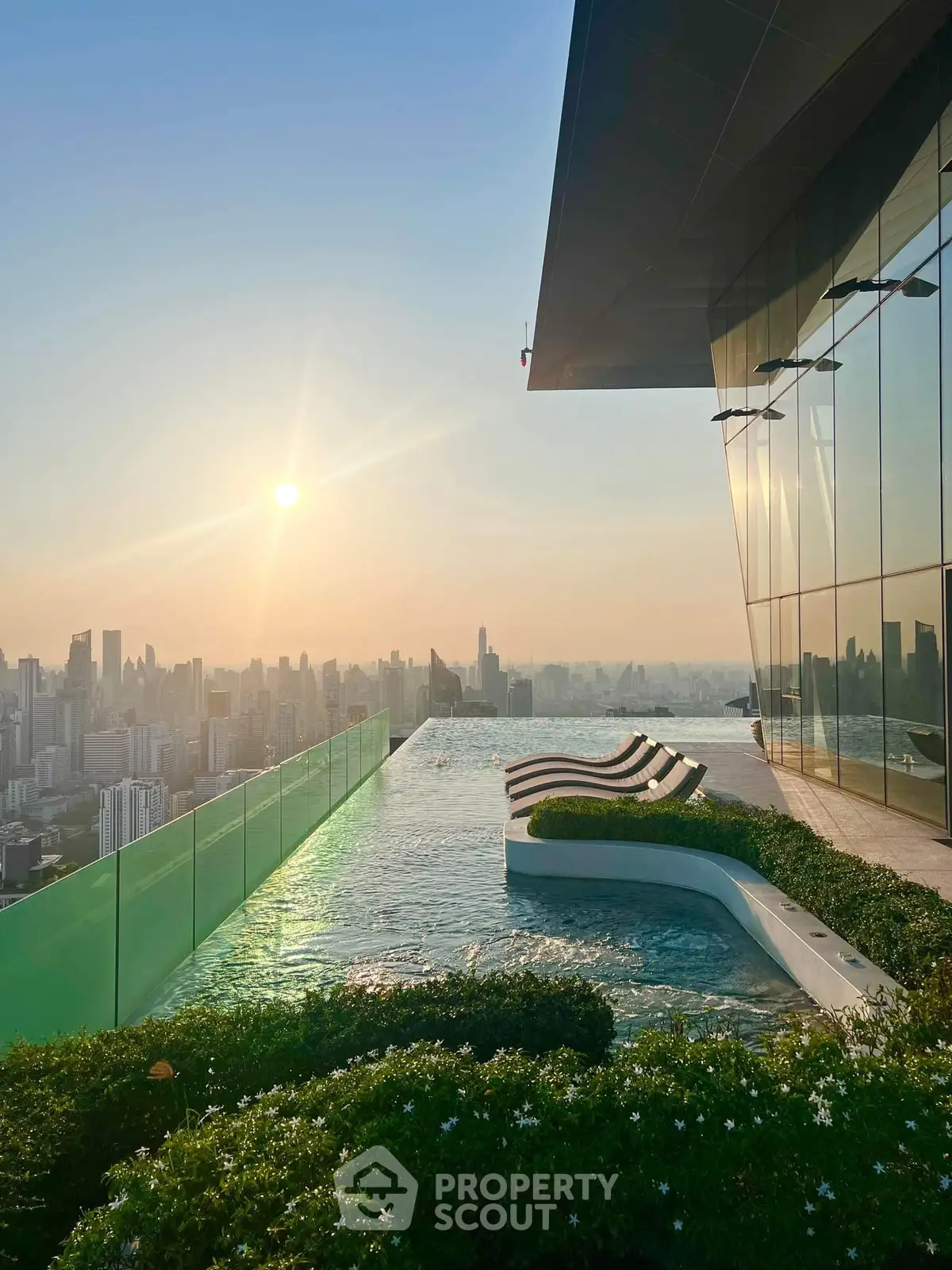 Stunning rooftop pool with panoramic city skyline view at sunset, perfect for luxury living.
