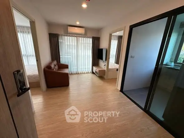 Modern apartment interior with open living room and bedroom, featuring sleek design and natural light.