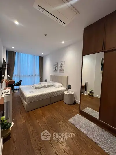 Spacious modern bedroom with wooden flooring, large bed, and stylish decor in a luxury apartment.