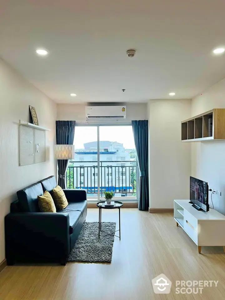 Modern living room with balcony view, stylish furniture, and natural light.