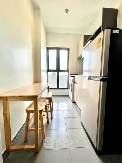Modern kitchen with sleek appliances and natural light, featuring a compact dining area and efficient layout.