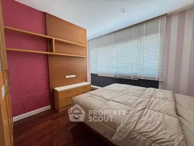 Cozy bedroom with modern design, featuring wooden flooring and built-in shelves.