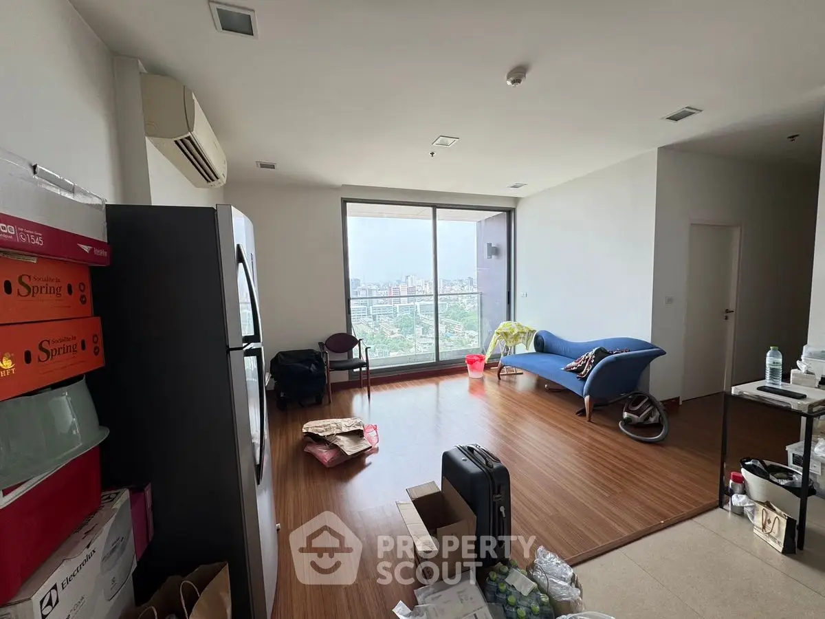Spacious living room with city view, modern furnishings, and large windows.