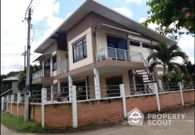 Modern two-story house with balcony and fenced yard in a suburban neighborhood.