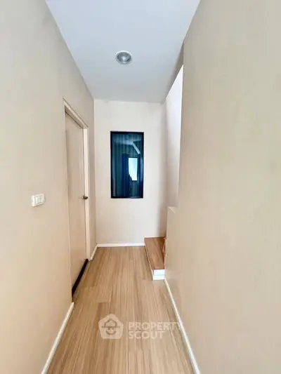 Minimalist hallway with wooden flooring and neutral walls