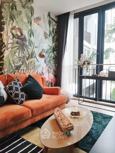 Stylish living room with vibrant jungle-themed wallpaper and modern furniture, featuring a cozy orange sofa and large windows.