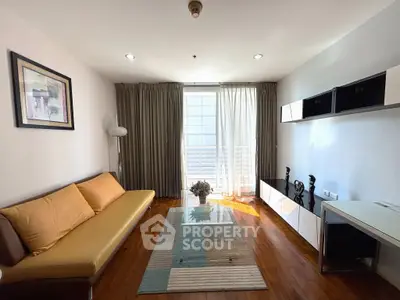 Stylish living room with modern decor, wooden flooring, and ample natural light from large windows.