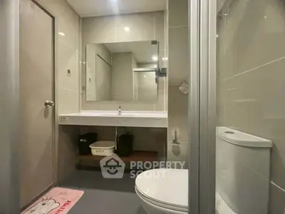 Modern bathroom with sleek design and large mirror, featuring a toilet and spacious sink area.