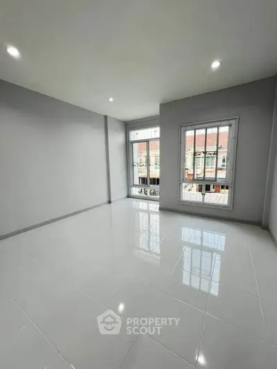 Spacious unfurnished room with large windows and glossy tiled floor, perfect for customization.